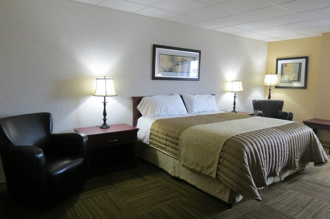 Guest room at Four Winds Motel with a made bed, lamps, and seating